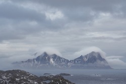 Clouds,fog and mist around the mountain peaks of the little island surrounded by the sea on a rainy winter day