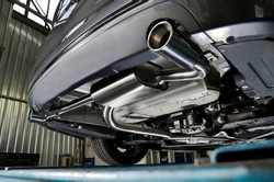 Sportive mufflers. Oval or round Car Exhaust Tailpipe chromed made of stainless steel on powerful sport car bumper. Exhaust silencer, metal fittings and pipes for the muffler