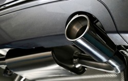 Titanium or steel sportive mufflers. Oval or round Car Exhaust Tailpipe chromed made of stainless steel on powerful sport car bumper. Exhaust silencer, metal fittings and pipes for the muffler