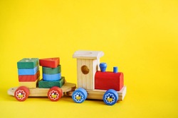 Bright toy wooden train on a yellow background