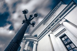 Vintage cast iron lamppost in front of a white classical building, Moscow, Russia