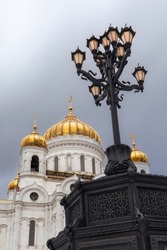 Vintage cast iron lamppost in front of a giant white Russian Orthodox cathedral with golden domes, Moscow, Russia