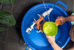 a toddler is playing with animal toys while taking a bath with a blue bucket of water