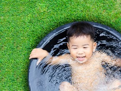cute baby boy taking water procedures in summer garden