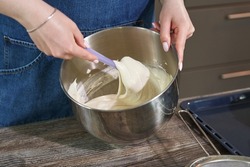 female hand kneading the dough in a bowl with a spatula