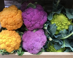 Romanesco broccoli and purple and orange cauliflower in a grocery. Variety of colorful vegetables in wooden boxes. Vegan health food concept