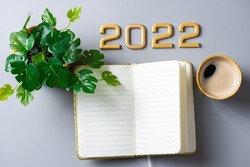 New year goals 2022 on desk. 2022 new year resolutions on gray table with coffee cup, notebook and plant. Resolutions, plan, goals, business concept. New Year 2022 template, copy space