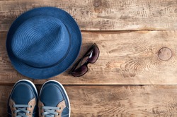Men's casual accessories hat, shoes and sunglasses on old wooden background with copy space. Hipster  or traveler outfit. Set of men's clothes. Top view