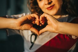 Detail of a woman making a heart with her hands while she is wearing a shirt from Peru. Sports concept.