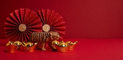 Chinese new year festival decoration over red background. Traditional lunar new year gold ingots, paper fans. Copy space, banner
