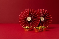 Chinese new year festival decoration over red background. traditional lunar new year gold ingots, paper fans. Copy space