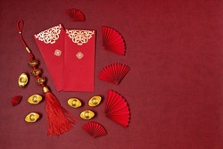 Chinese new year festival decoration. Traditional lunar new year red pockets, paper fans and gold ingots with text meaning fortune, prosperity, wealth. Flat lay, top view