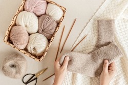 Craft hobby background with yarn in natural colors and handmade socks. Recomforting hobby to reduce stress for cold fall and winter weather. Mock up, top view
