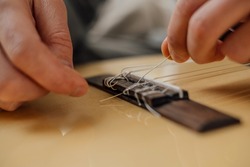 Hands of a young man changing the string on an acoustic guitar.