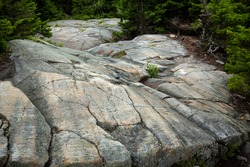Scoured granite bedrock, with glacial striations and grooves, and scratches from snow machine treads, at the bald summit of Mt. Kearsarge in Wilmot, New Hampshire.