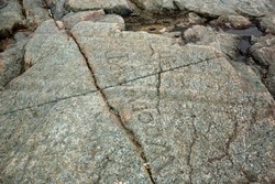 Scoured granite bedrock, with glacial striations and grooves, and destructive name carvings on the bald summit of Mt. Kearsarge in Wilmot, New Hampshire.