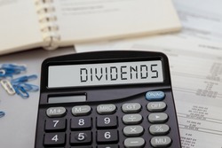 Calculator with the word DIVIDENDS on display. Business, tax and financial concept