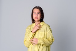 Anxious and scared teen girl looking frightened, staring at camera with nervous face, fear of consequences, standing alarmed against gray background