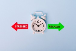 stressed vs relaxed. Red arrow and green arrow- direction indicator - choice of stressed or relaxed. Concept of choice. Two Arrows and clock on blue background, top view