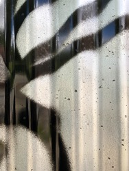 Close up of corrugated metal panel textured background with black spray paint dripping down.