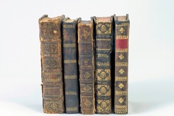 Stack of antique books bound in ancient leather on a white background.
