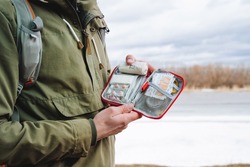 A bag with medicines, a first-aid kit in the hands of a tourist, tablets in a package, a patch for a wound, a band-aid, emergency medical care in the forest, health protection. High quality photo