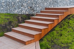 Wooden staircase assembled from boards, landscape design in a private house, brown staircase, descent up the steps, green grass lawn. High quality photo