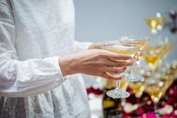 Glasses of champagne in the hands of a waitress girl, light sparkling wine, distribution of glasses with whiskey, cocktail party, alcoholic beverages spill. High quality photo