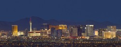 Horizontal photo of Las Vegas with mountain backdrop at night.