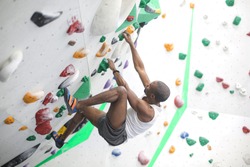 Sportive man climbing a wall in a climbing centre