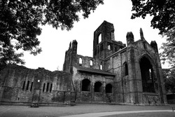 A Black & White general view of the Kirkstall Abbey framed by trees in Leeds, England. 