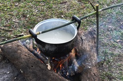 Cooking rice using pot in outdoor nature. Food Camping cooking over a fire using dry firewood and use stone as stove stand.