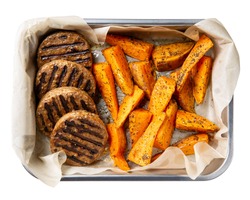 Grilled meat free plant based cutlets with sweet potato wedges in metal baking dish isolated on white. Healthy vegan or vegetarian food concept. Top view.