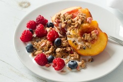 Tasty bowl of fruits, granola and yogurt. Healthy snack served for one on a white plate, top view