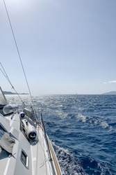 Sailboat in Aegean sea. Sailing on yacht. Yachting sport in the morning. Yacht sailing in an open sea. Close-up view from the deck to the bow and sails. selective focus
