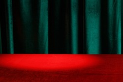 Modern background with empty red cloth table and green draped velvet curtains. Template for advertising, presentation, cosmetic products. Mockup, texture