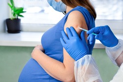 Doctor giving COVID -19 coronavirus vaccine injection to pregnant woman. Doctor Wearing Blue Gloves Vaccinating Young Pregnant Woman In Clinic. People vaccination concept. Covid vaccination campaign