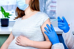 Pregnant Vaccination. Doctor giving COVID -19 coronavirus vaccine injection to pregnant woman. Doctor Wearing Blue Gloves Vaccinating Young Pregnant Woman In Clinic. People vaccination concept. 