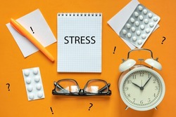 Blank of Notepad with the Word Stress, Pen, Clock and Antidepressants on orange Background. Top view, Flat lay. Copy space. Stop Depression. Education, Exam, Work Stress or Tension concept.