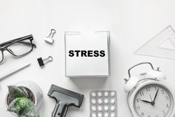 Blank of Notepad with the Word Stress, Pen, Clock and Antidepressants on white Background. Top view, Flat lay. Copy space. Stop Depression. Education, Exam, Work Stress or Tension concept.