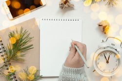 Back to life, goal list concept. Woman's hand writing in empty notebook. Resolutions, plan, goals, checklist, idea concept. Top view, flat lay, copy space. 2022. Christmas, New Year.