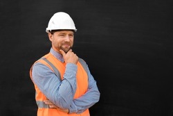 Male Engineer in a White Hard Hats and Orange West. Handsome Confident Build Worker Isolated on Blank Black Background. Copy Space. He Work in a Heavy Industry Manufacturing Factory. Mechanic Service.