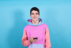 young teenager boy with mobile phone isolated on blue background