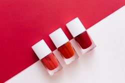 Bottles of red nail polish on red and white background. Manicure and pedicure concept. Flat lay, top view, copy space