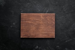 Kitchen board on black stone background. Top view. Free space for your text.