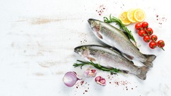 Raw fish with vegetables on a white wooden background. Fish trout. Top view. Free space for your text.