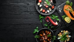 Set of Seafood Dishes. Seafood on a plate. On a black wooden background. Top view. Free copy space.