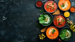 Set of colored soups. Spinach soup, tomato cream soup and carrot puree soup. Healthy food. On a black stone background.