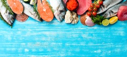 Seafood background: salmon, tuna, caviar, oysters, dorado fish and shellfish on a blue wooden background. Top view. Seafood.