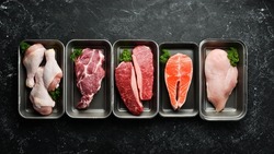 Set of fresh raw meat and fish in plastic boxes: veal, salmon steak, chicken, pork. Banner for the supermarket. On a dark background. Organic food.